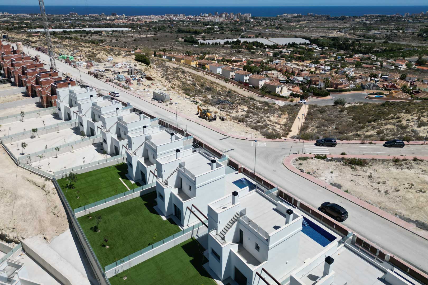 Vista aérea de villas contemporáneas con jardines privados, piscinas individuales y azoteas transitables, ubicadas en una colina con vistas panorámicas hacia el mar.