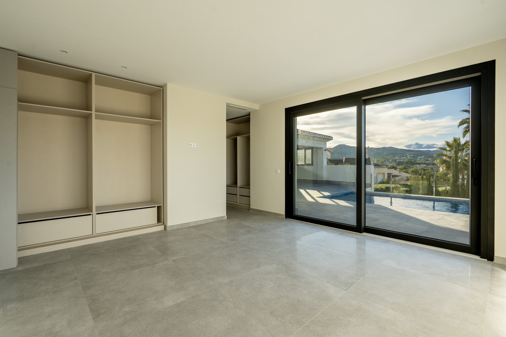 Dormitorio luminoso con armario empotrado y acceso a la piscina mediante puerta corredera.