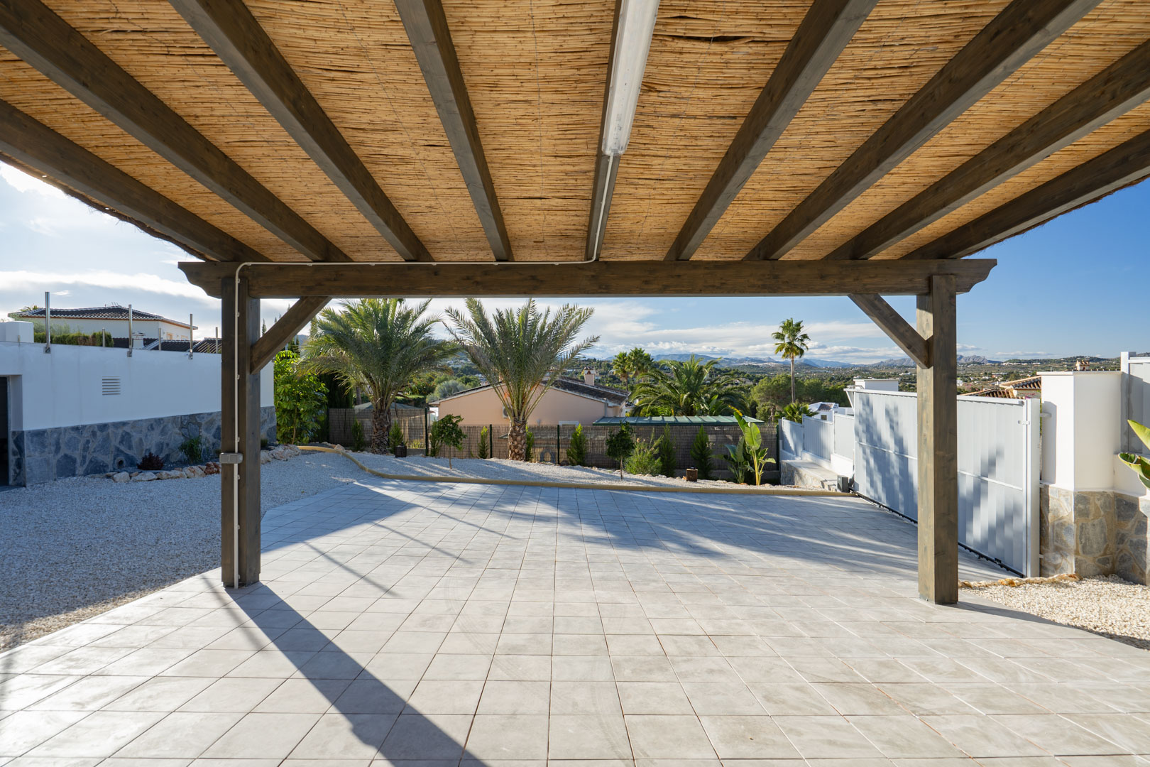 Pérgola con estructura de madera y cubierta de caña, sobre suelo de baldosas en villa de Jávea.