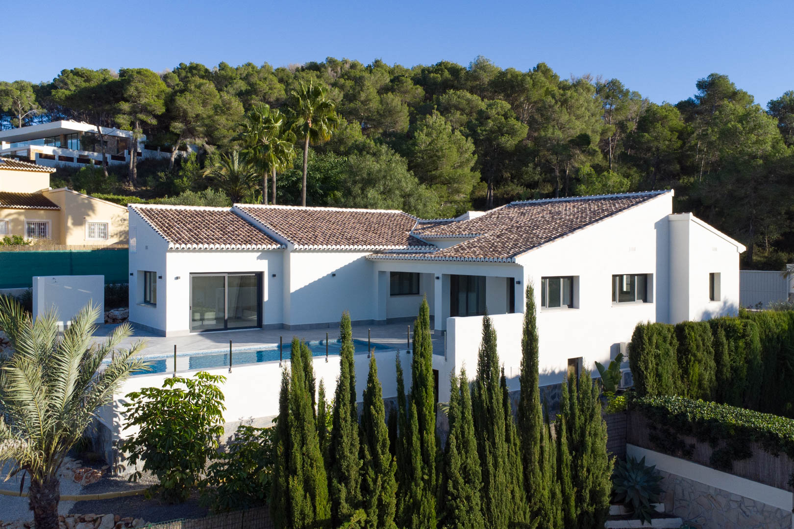 Vista exterior de la villa en Piver, Jávea, destacando su diseño moderno, piscina privada y entorno natural exuberante.