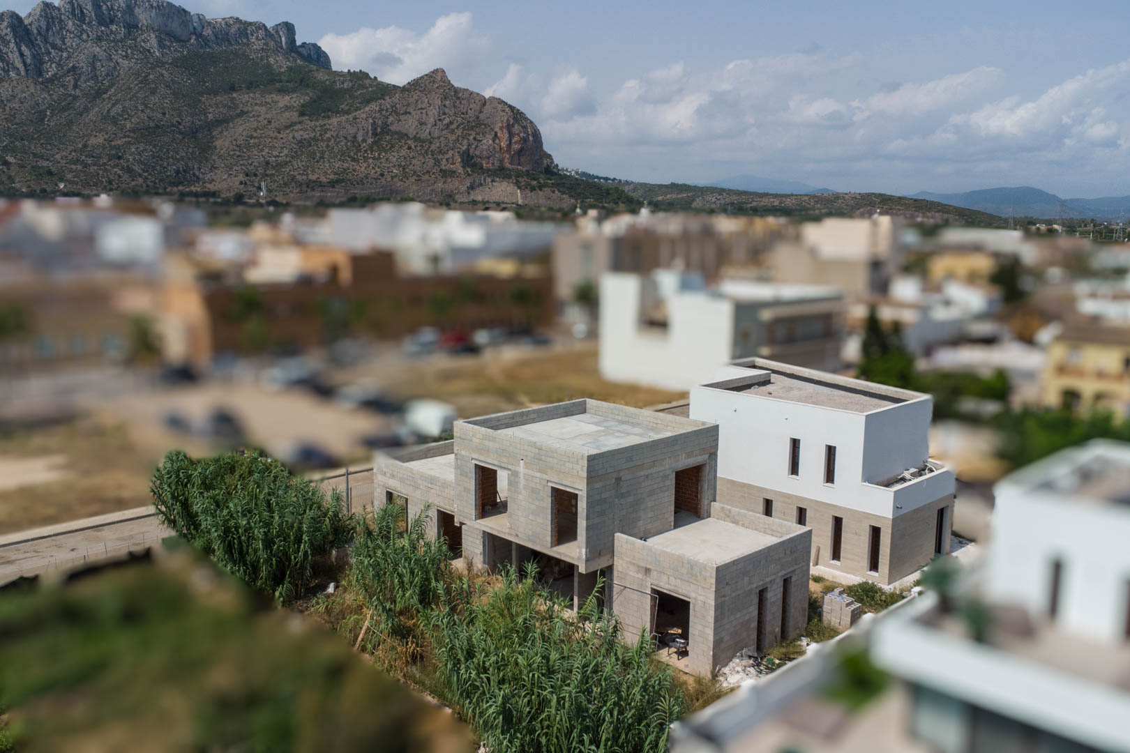 Vista elevada de la villa en fase de construcción con estructura de bloques, situada frente a la montaña de Segaria en un entorno residencial.