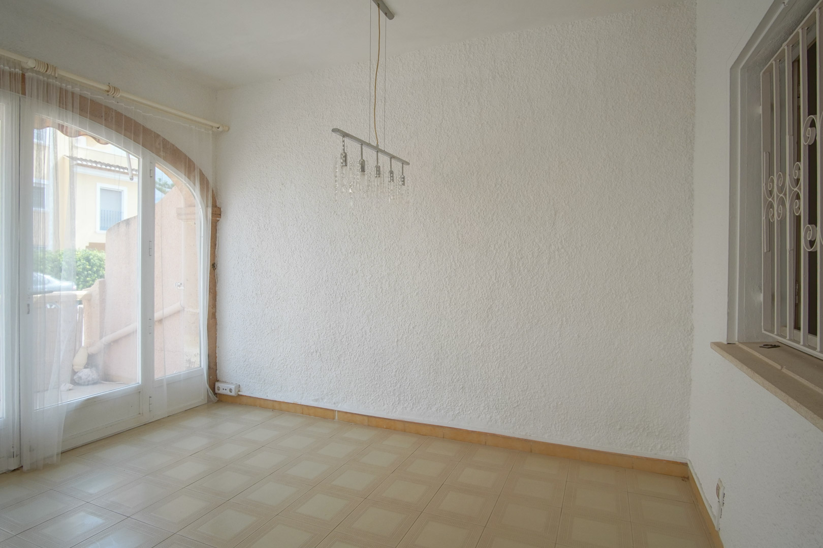 Salón con paredes texturizadas, suelos de gres y un gran ventanal de arco que comunica con el exterior, aportando luz natural.