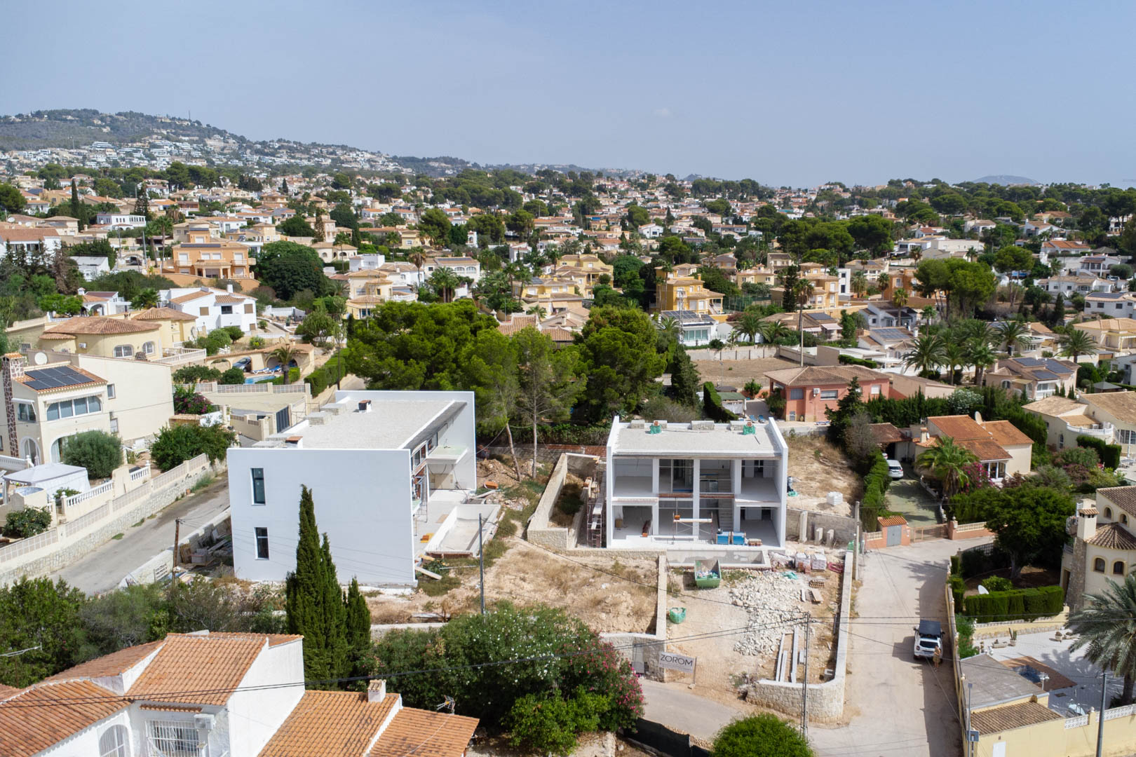 Vista aérea de la villa en fase de construcción, mostrando su estructura moderna de dos niveles y la parcela llana integrada en la urbanización de Calpe.