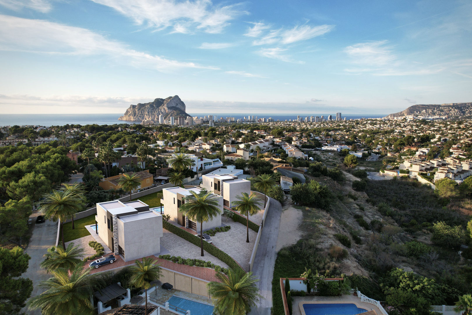 Vista aérea de tres villas modernas con arquitectura cúbica, destacando las vistas panorámicas al Peñón de Ifach y el skyline costero de Calpe.