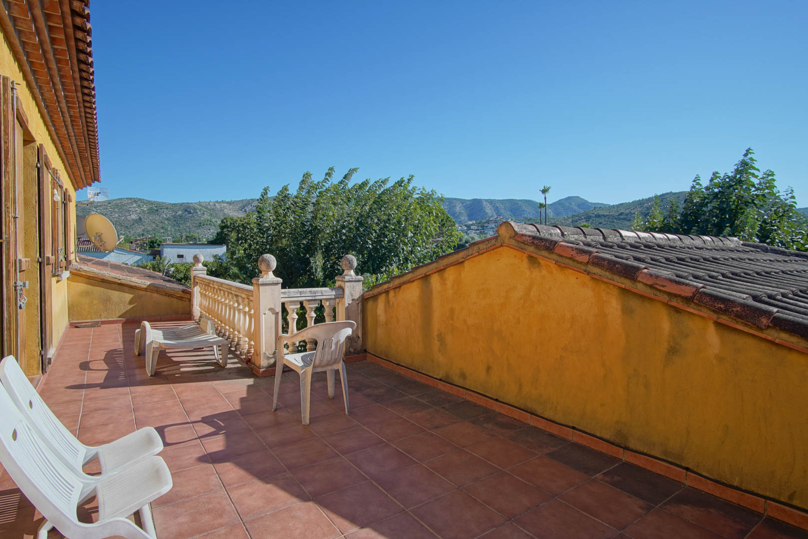Terraza superior con suelo de gres rústico y balaustrada de piedra, ofreciendo vistas despejadas a la montaña de Segaria y el entorno natural.