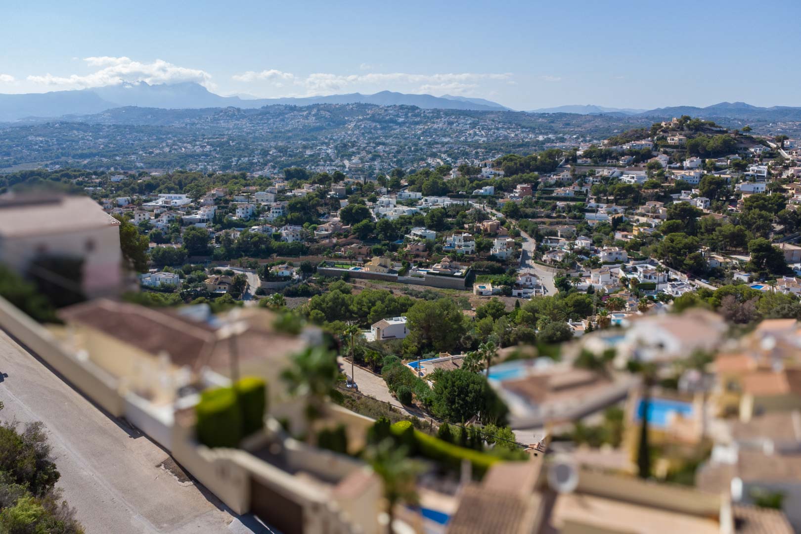 Vista panorámica elevada sobre la zona residencial de El Portet, mostrando la densidad de vegetación mediterránea y las montañas al fondo bajo un cielo despejado.