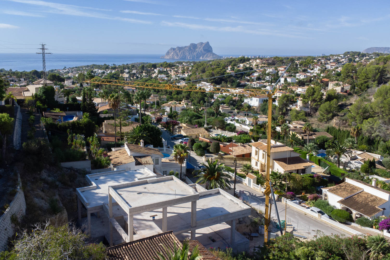 Vista panorámica desde la estructura en construcción hacia el mar Mediterráneo y el Peñón de Ifach, rodeada de la consolidada urbanización San Jaime.