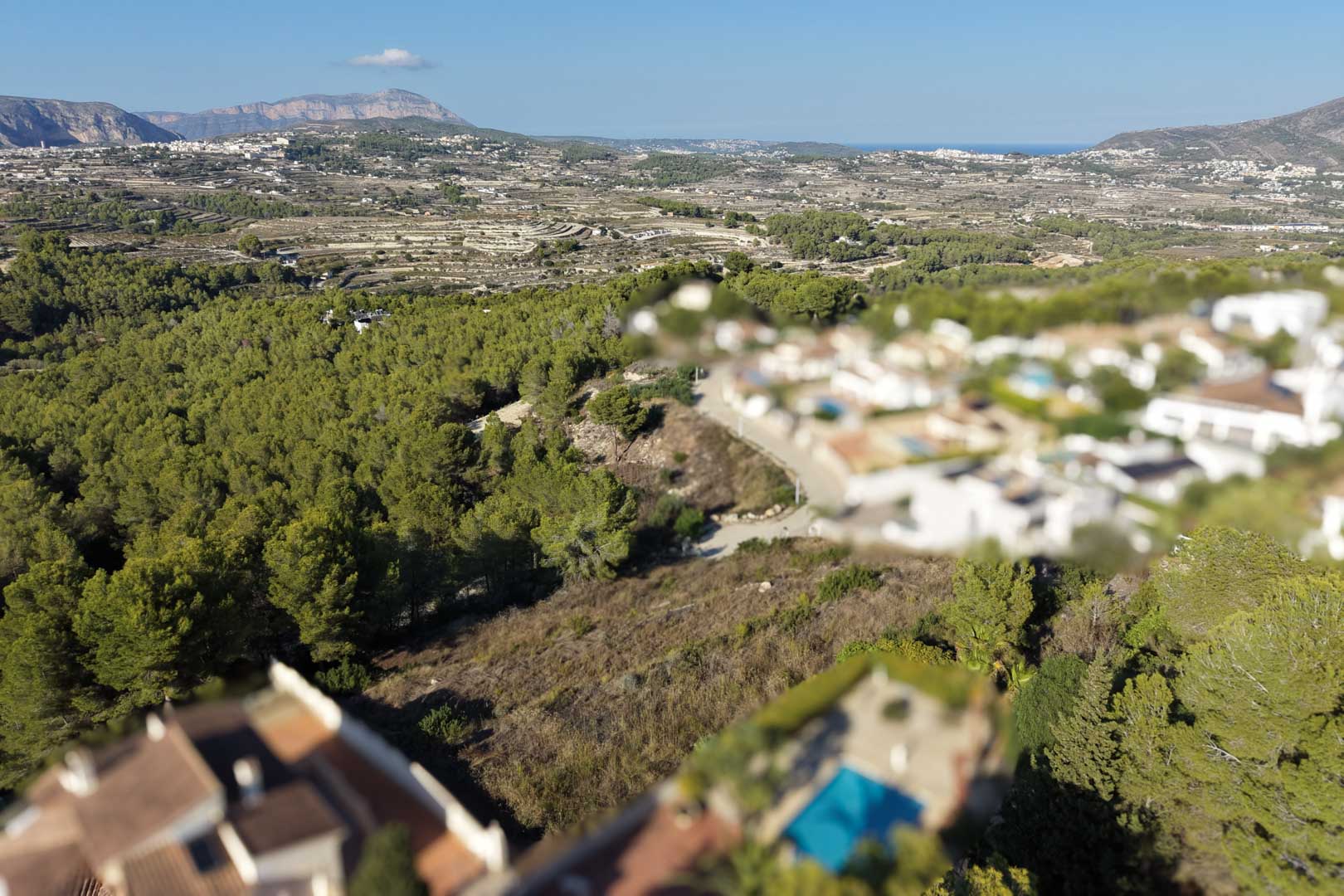 Vista aérea de la parcela urbana elevada con vegetación natural, ofreciendo vistas panorámicas al valle de Moraira y el mar Mediterráneo al fondo.