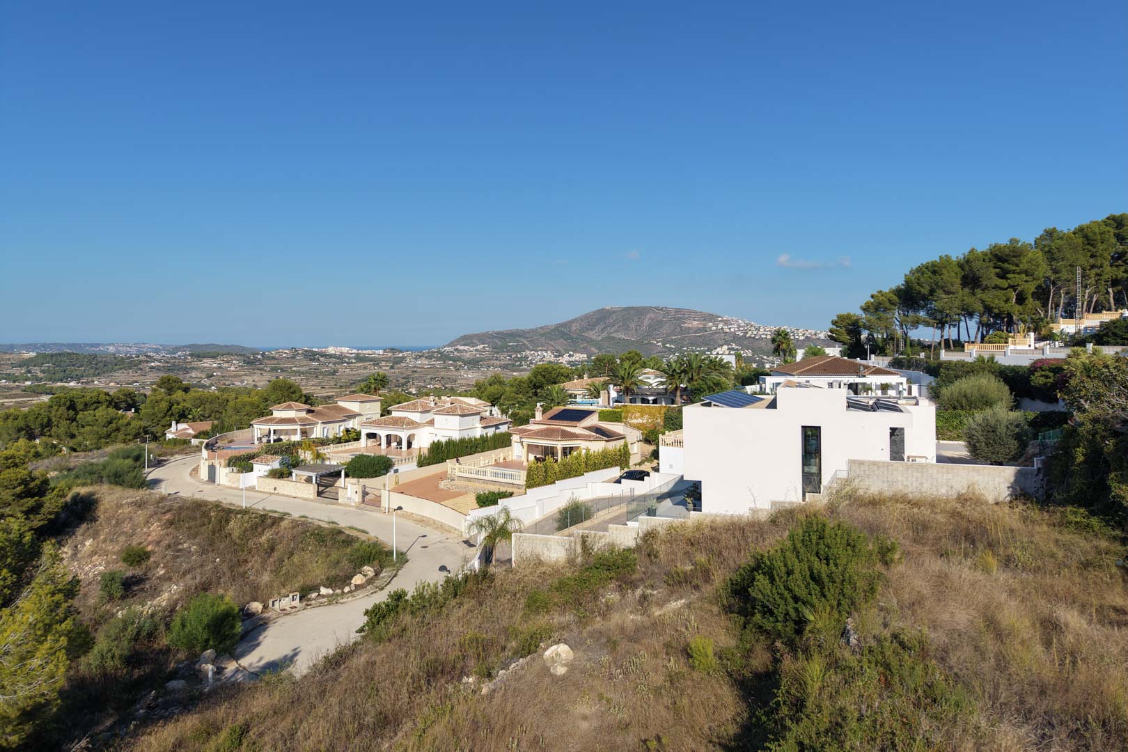Vista panorámica elevada del entorno residencial en Moraira, destacando la orografía del terreno y las vistas abiertas hacia las montañas y el mar.