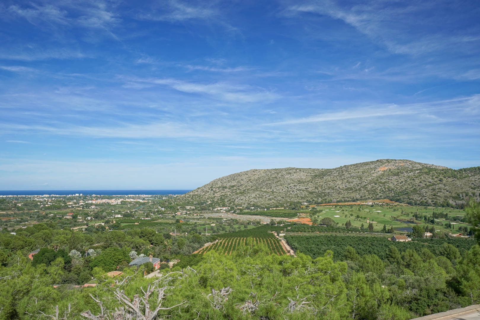 Vistas panorámicas desde la propiedad que abarcan el campo de golf La Sella, el valle agrícola y el horizonte del mar Mediterráneo bajo un cielo despejado.