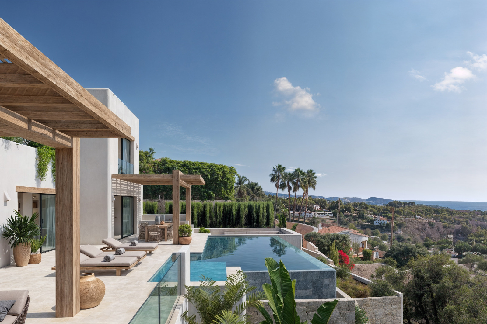Terraza exterior con piscina infinita de mosaico, pérgolas de madera y vistas panorámicas al mar. La fachada blanca de estilo ibicenco se integra con la vegetación mediterránea.