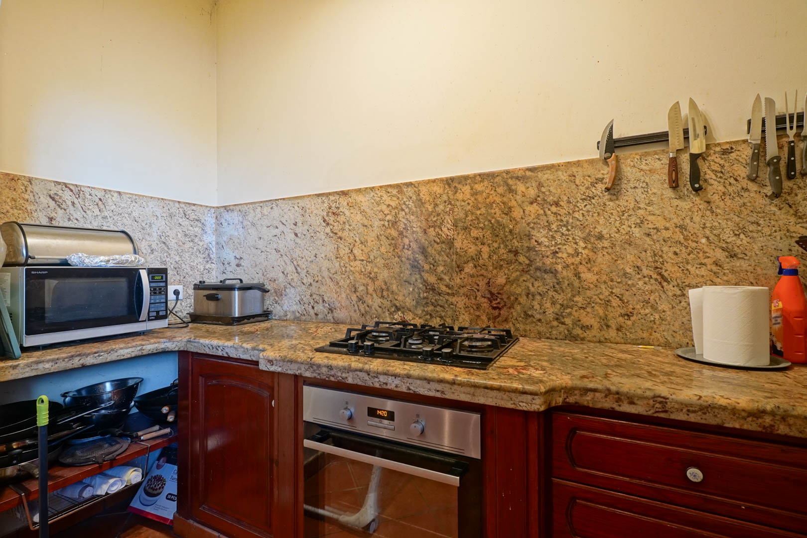 Cocina con encimera y frontal de granito veteado, equipada con placa de gas, horno de acero inoxidable y armarios de madera clásica.