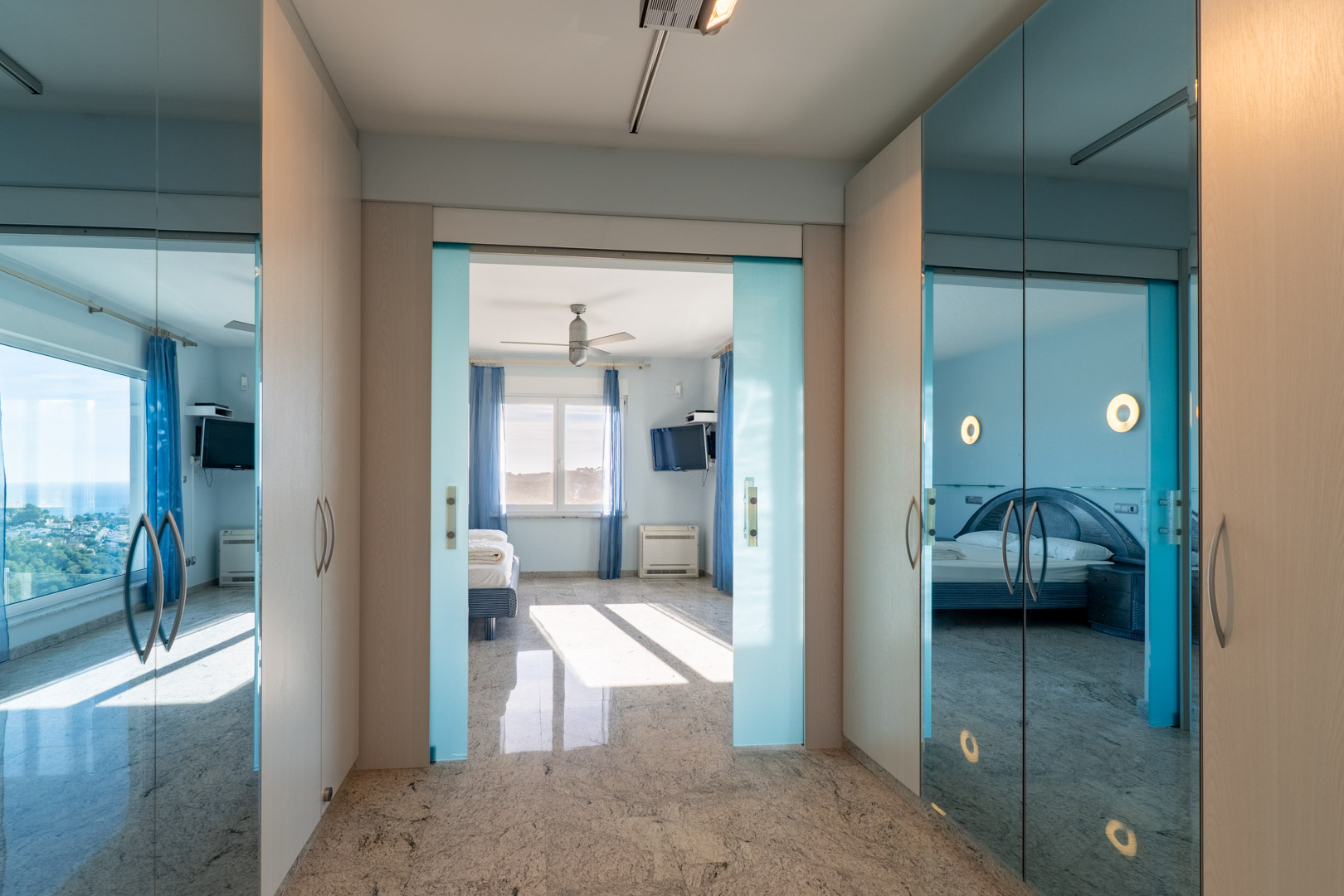 Entrada a dormitorio con armarios de espejo y puertas correderas azules.