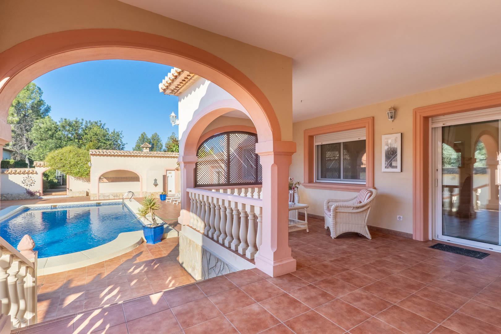 Amplia naya cubierta con arcos mediterráneos y suelos de terracota, con vistas directas a la piscina privada y acceso al interior mediante puertas acristaladas.