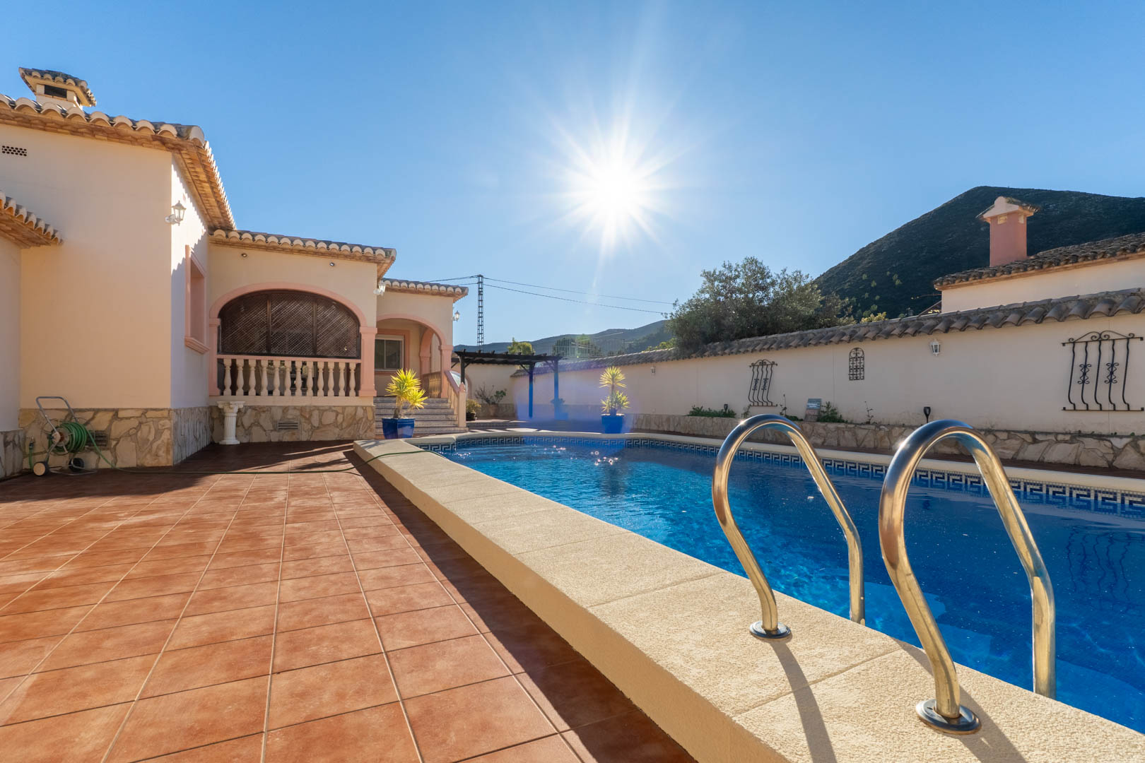Piscina privada rodeada de una amplia terraza de gres porcelánico, con vistas a las montañas y acceso directo a la naya arqueada de la villa mediterránea.