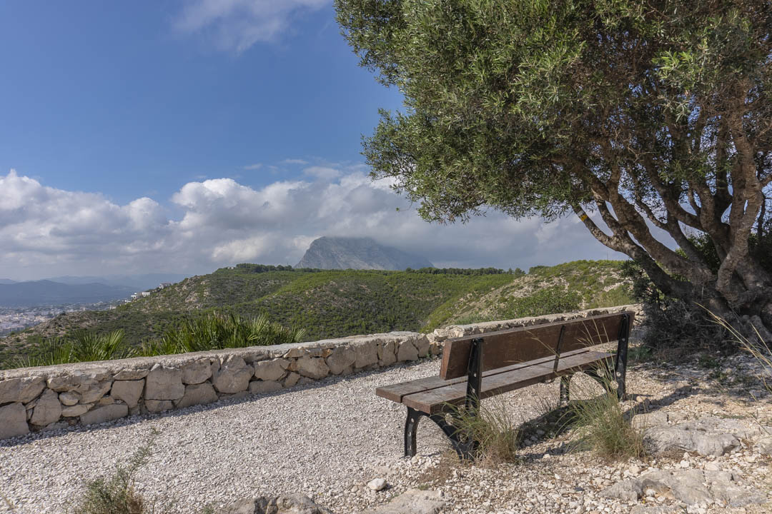 Mirador con banco de madera y murete de piedra natural que ofrece vistas despejadas al macizo del Montgó y al entorno natural de Jávea.