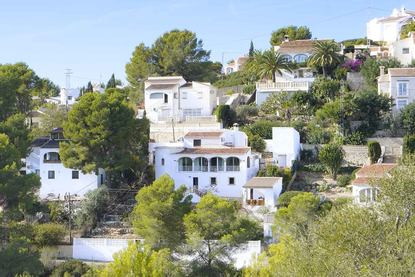 Vista exterior de la villa en Pinomar, destacando su arquitectura de niveles con naya de arcos, fachadas blancas y entorno arbolado mediterráneo en Jávea.
