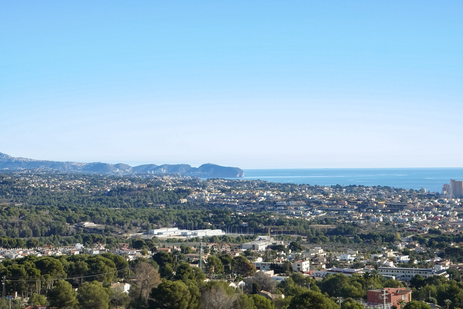 Vista panorámica desde la propiedad hacia la costa mediterránea, mostrando el Cap d’Or en Moraira y el entorno arbolado de Calpe bajo un cielo despejado.