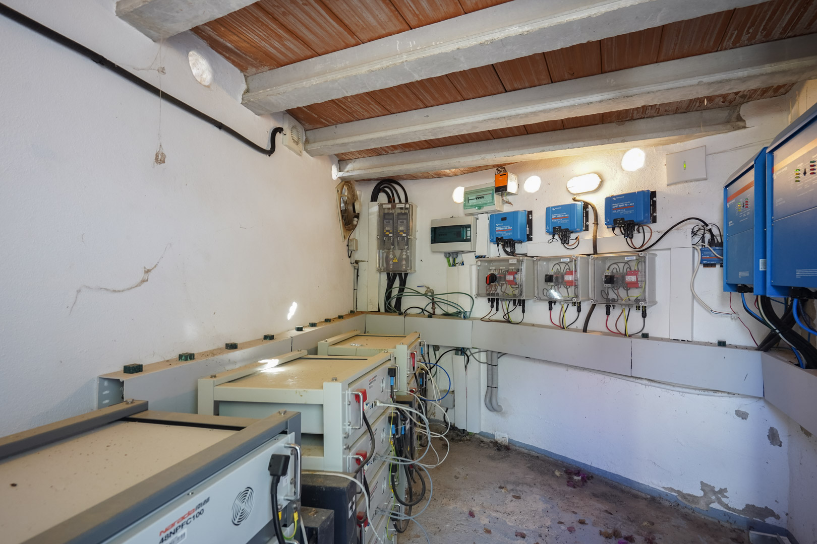 Cuarto técnico con sistema fotovoltaico de 30 kW, inversores Victron Energy y torres de baterías de litio Narada bajo un techo de vigas de madera.