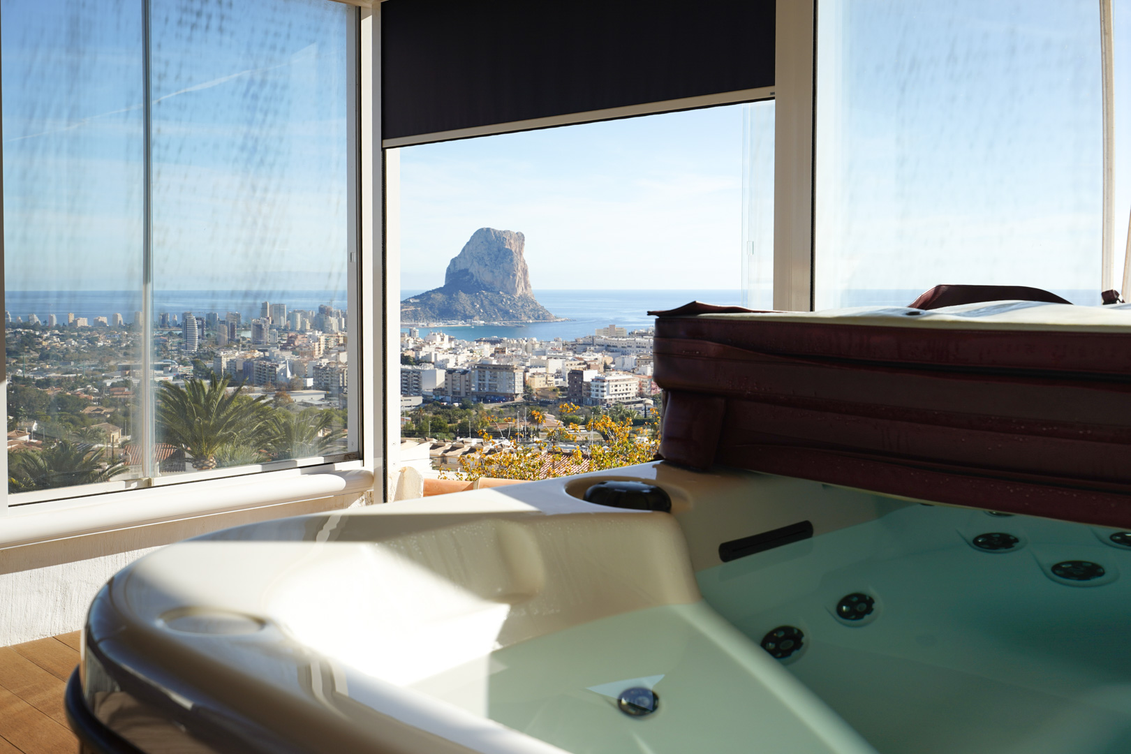 Jacuzzi de seis plazas en nivel superior, con cerramiento de cristal y vistas panorámicas al Peñón de Ifach, el skyline de Calpe y el mar Mediterráneo.