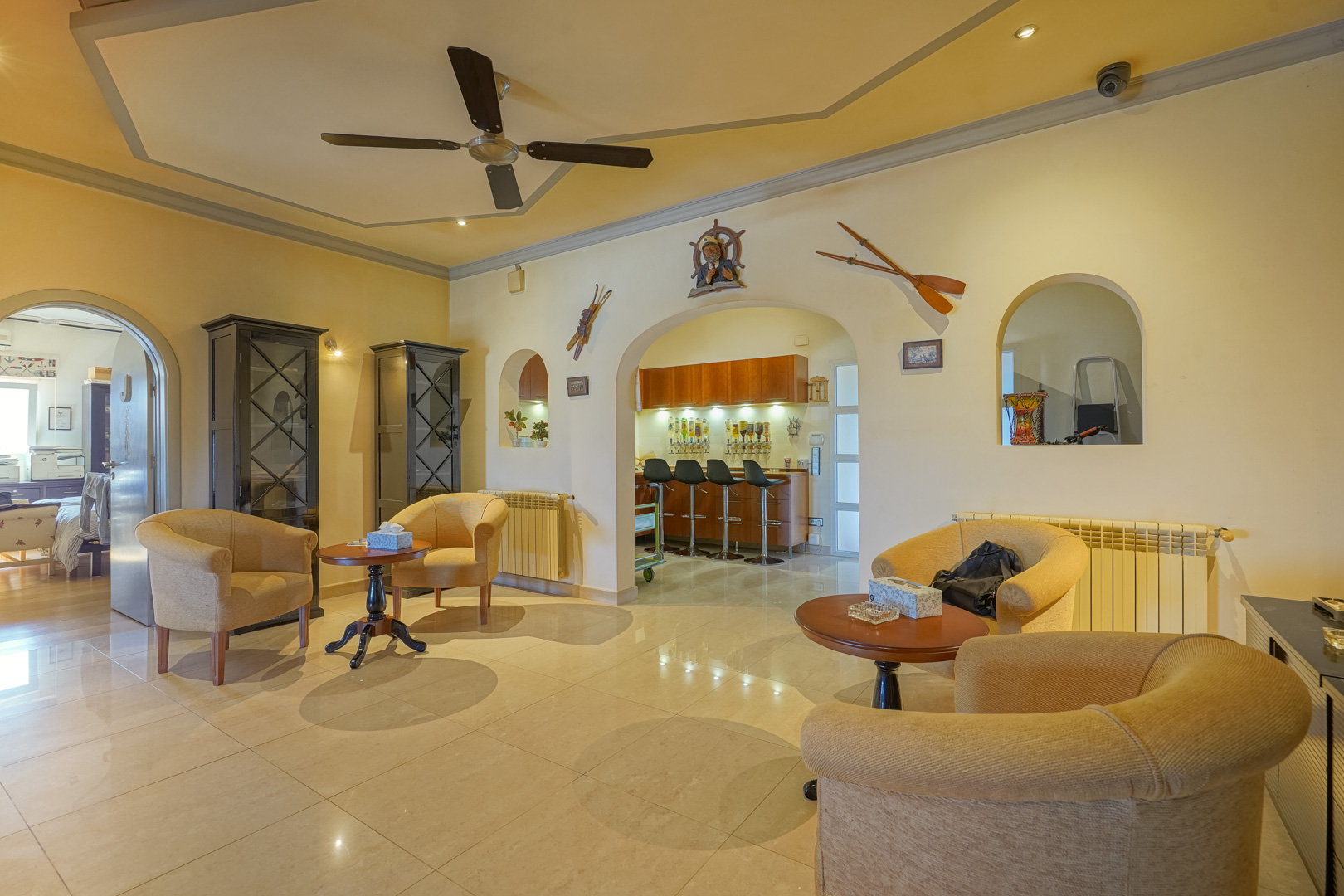 Salón con techos altos y ventilador, que destaca por sus arcos decorativos y un bar integrado con mobiliario de madera y detalles de temática náutica.