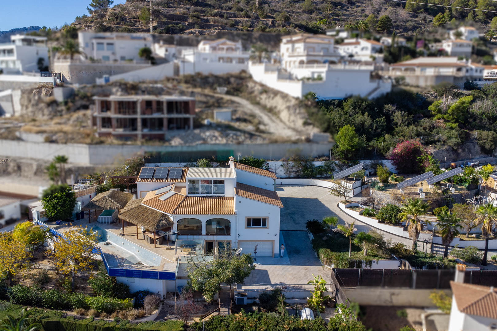Vista aérea de la propiedad destacando las tres torres solares motorizadas, la amplia zona de acceso pavimentada y las terrazas con cubiertas de brezo junto al área de piscina.