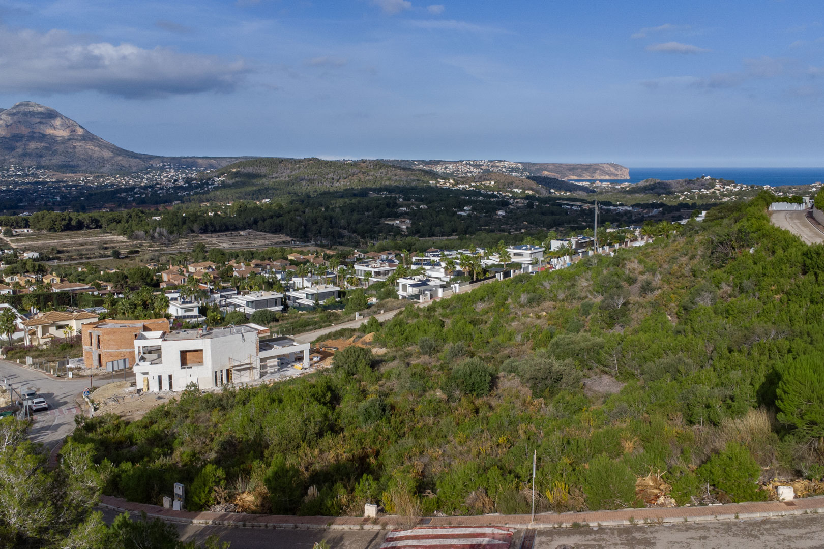 Vista elevada de la parcela en Monte Olímpico, mostrando el macizo del Montgó y el mar Mediterráneo junto al Cabo de San Antonio en el horizonte.