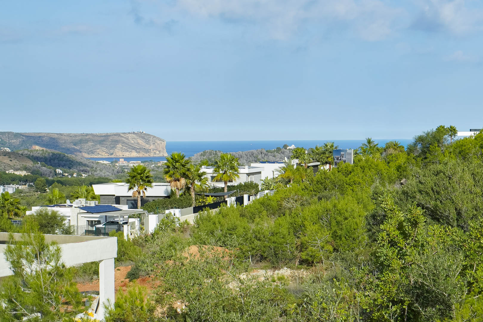 Vistas panorámicas al mar Mediterráneo y al Cabo de San Antonio desde la parcela, rodeada de villas modernas y vegetación autóctona en Monte Olímpico.