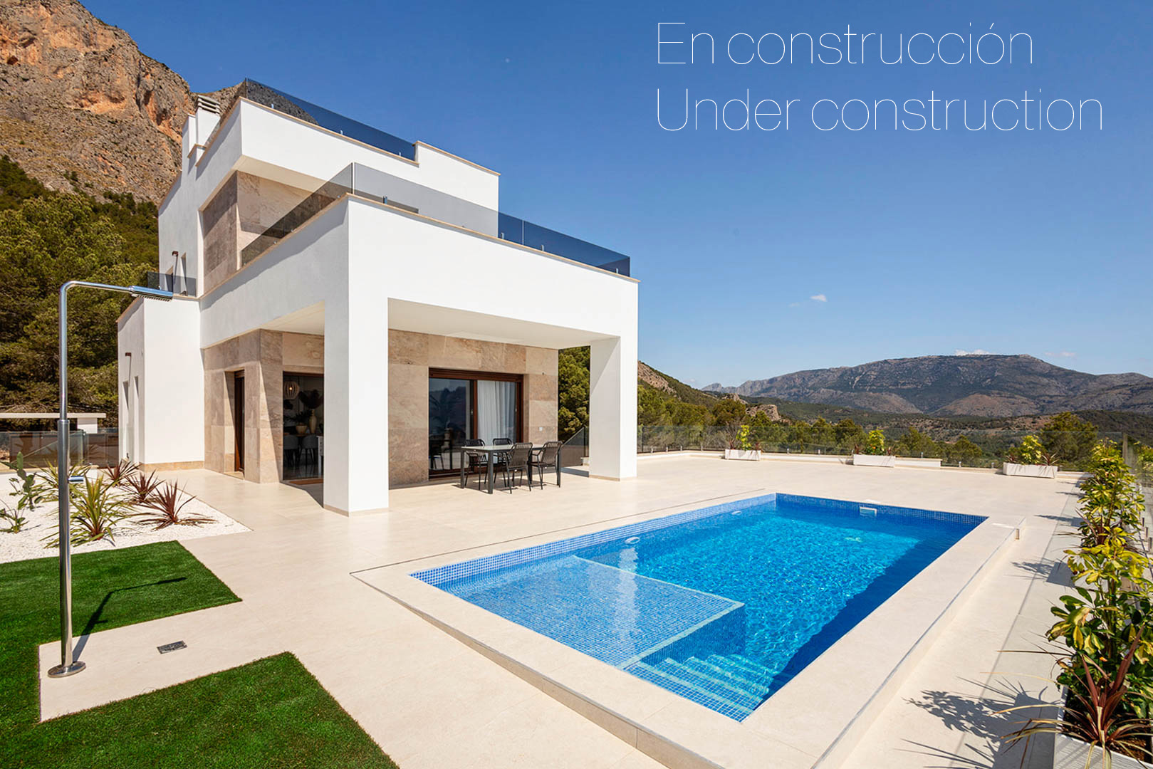 Exterior de villa moderna con piscina privada, amplias terrazas de gres porcelánico y fachada con detalles en piedra natural frente a vistas de montaña.