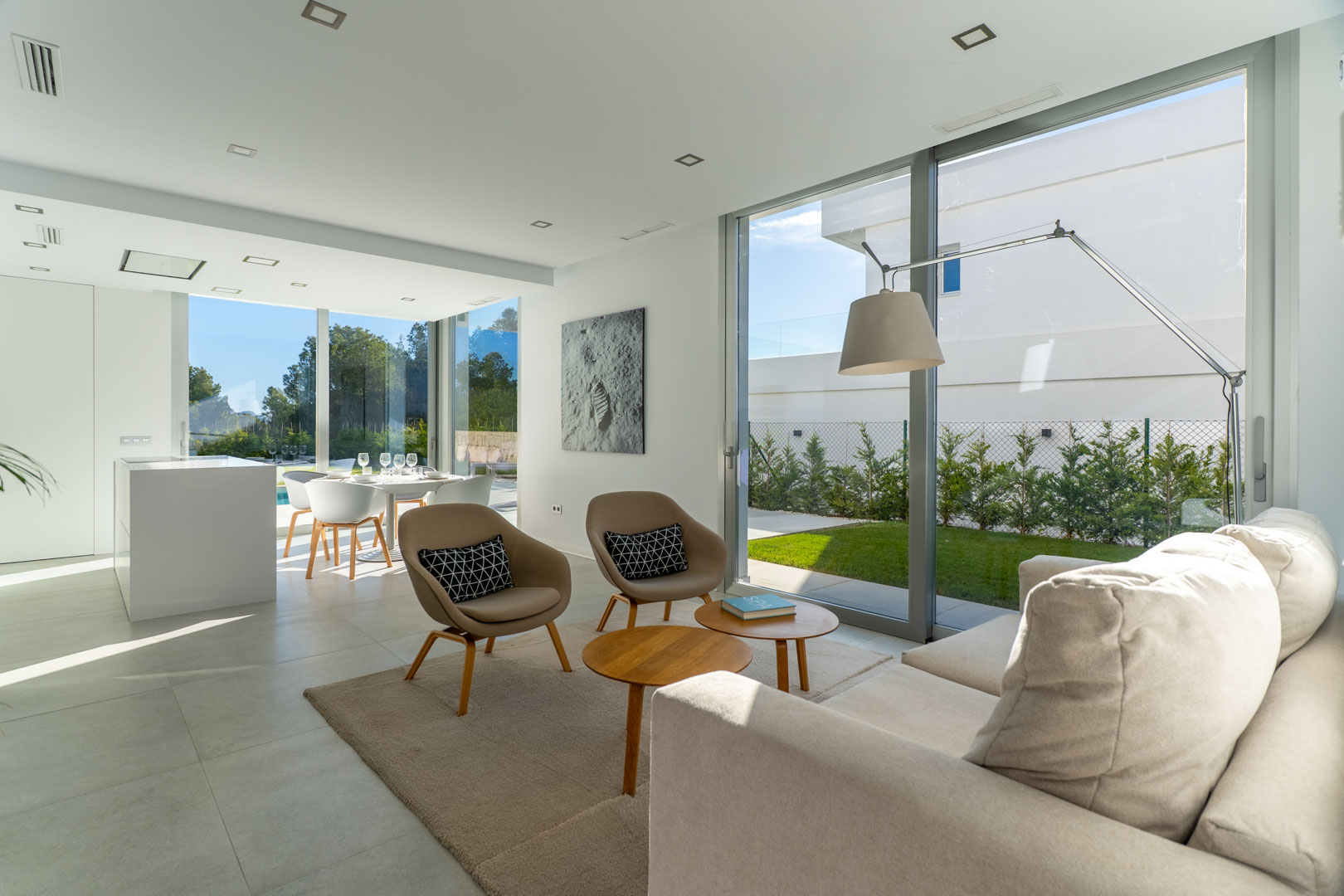 Salón-comedor diáfano con amplios ventanales de suelo a techo, mobiliario de diseño en tonos neutros y acceso directo al jardín privado.