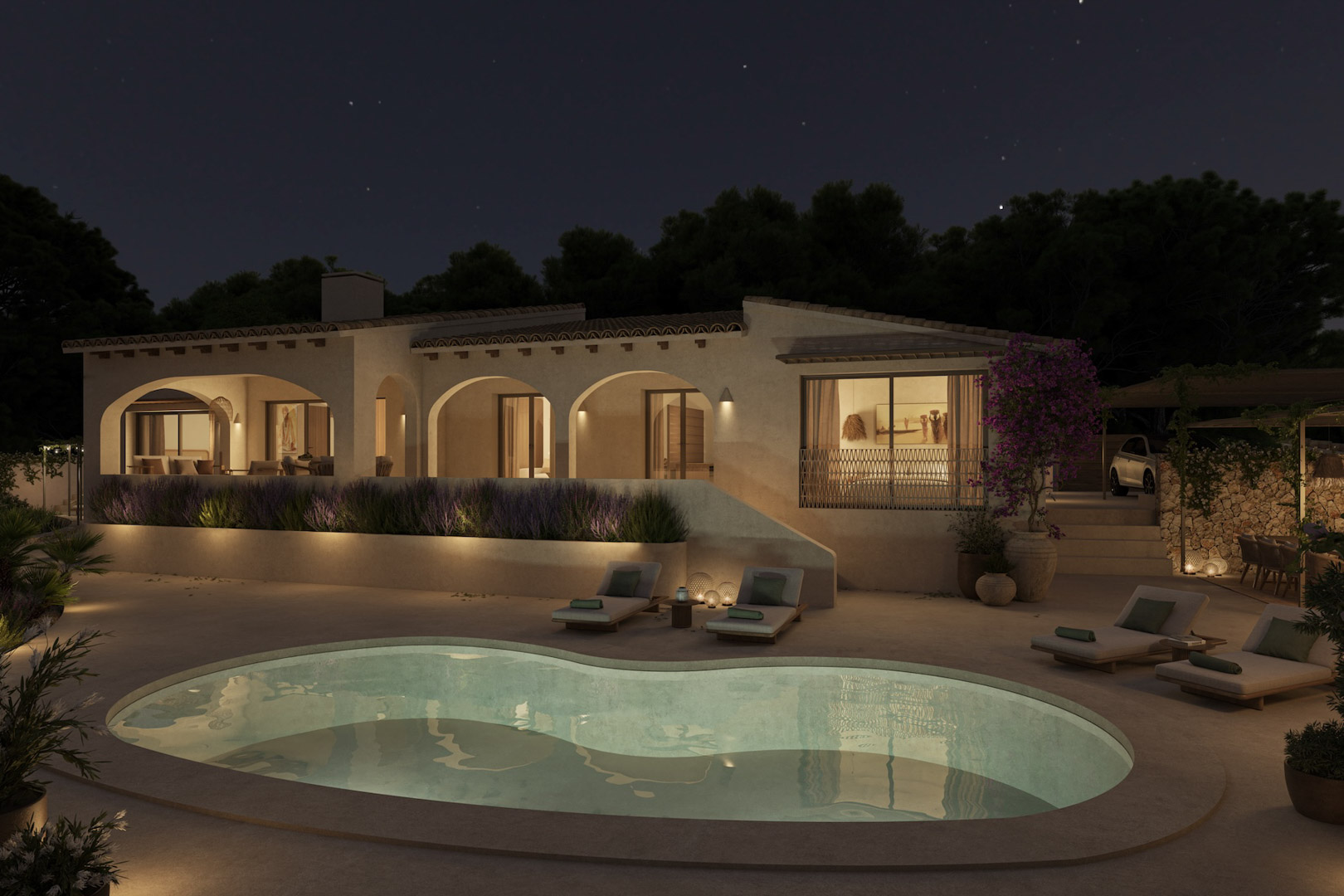 Vista nocturna de la fachada mediterránea con porches de arcos, piscina de forma orgánica iluminada y zona de solárium rodeada de lavanda y vegetación.