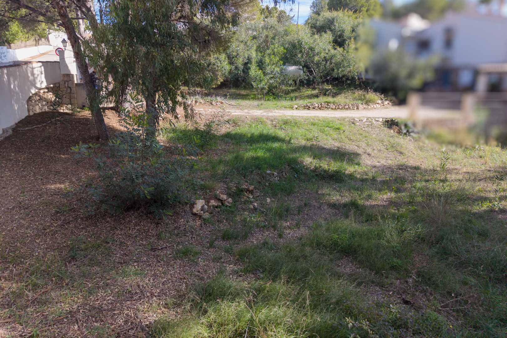 Parcela urbana con desnivel suave, vegetación autóctona y pinos. Incluye muros de piedra natural y acceso directo desde una calle residencial tranquila en Moraira.