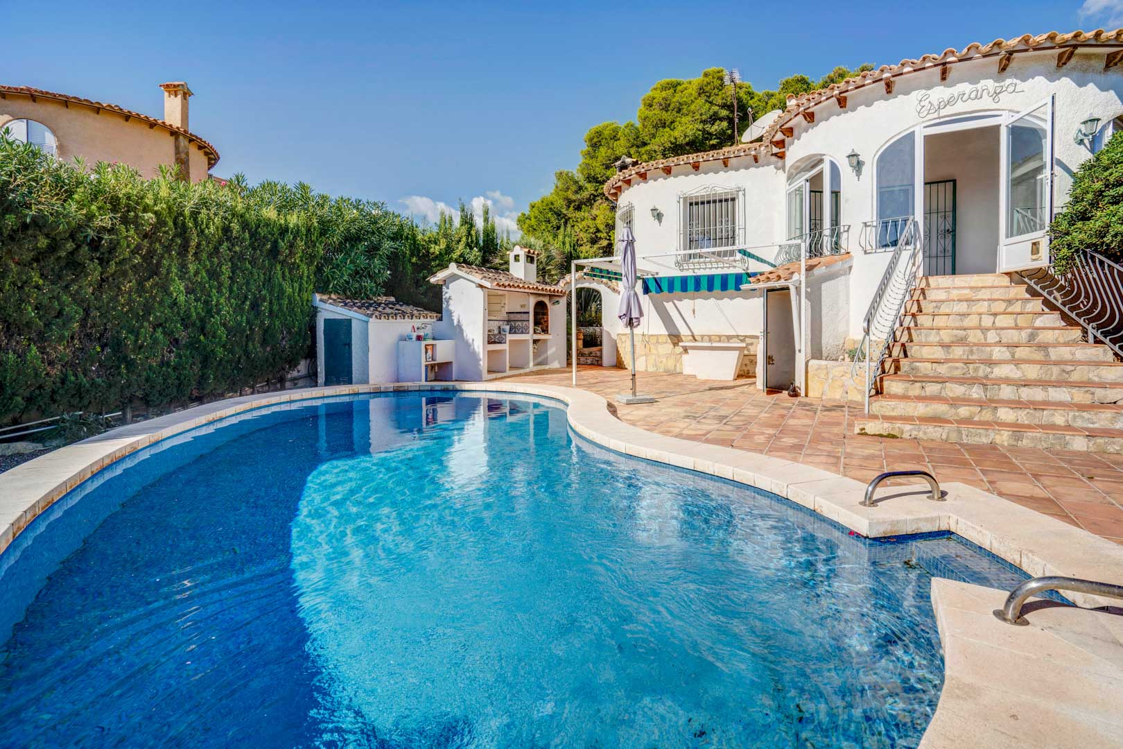 Piscina privada rodeada de una amplia terraza de gres, con zona de barbacoa exterior y acceso directo a la vivienda mediante escaleras de piedra.