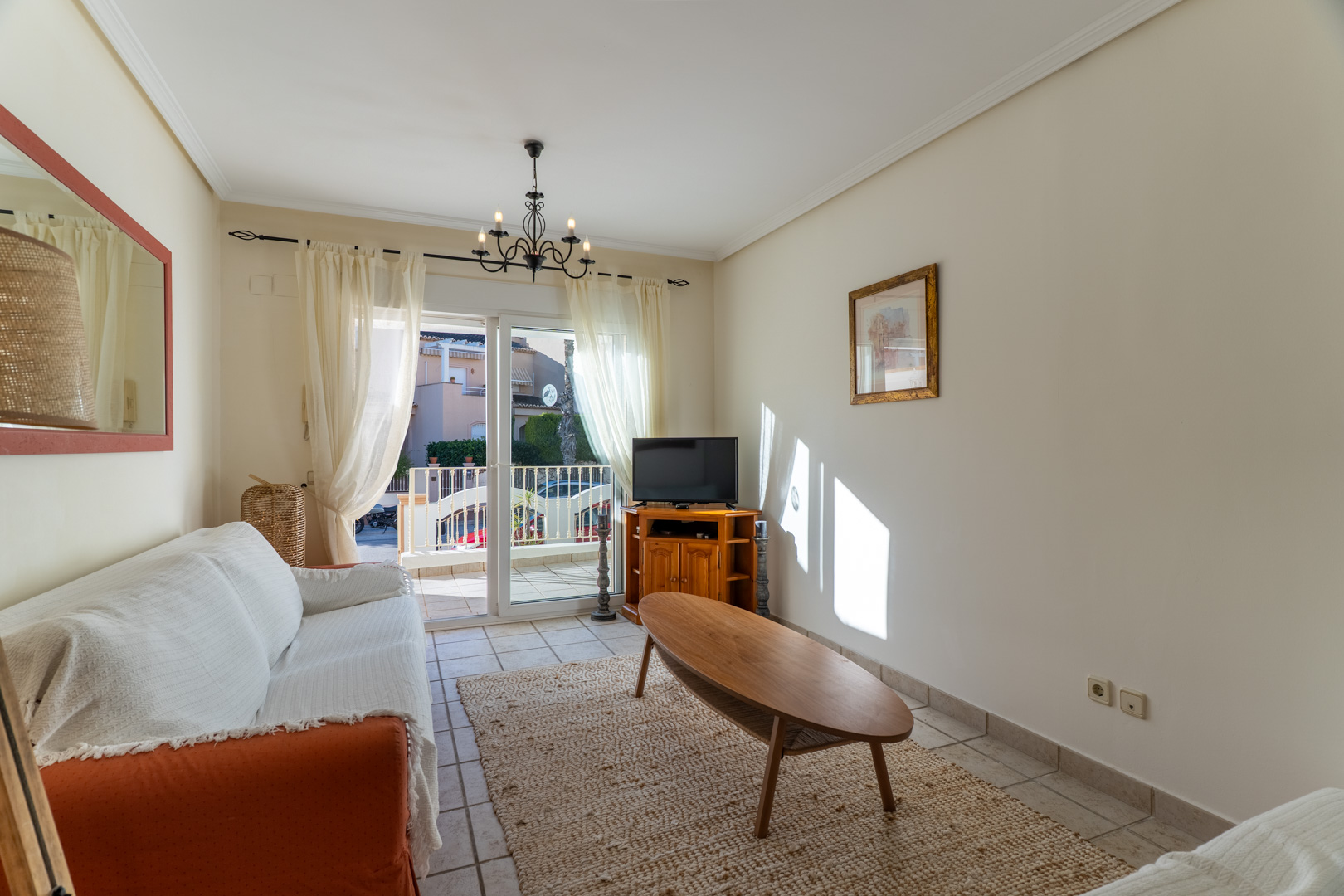 Salón luminoso con suelos cerámicos, mesa de centro ovalada de madera y acceso directo a la terraza privada a través de puertas correderas.