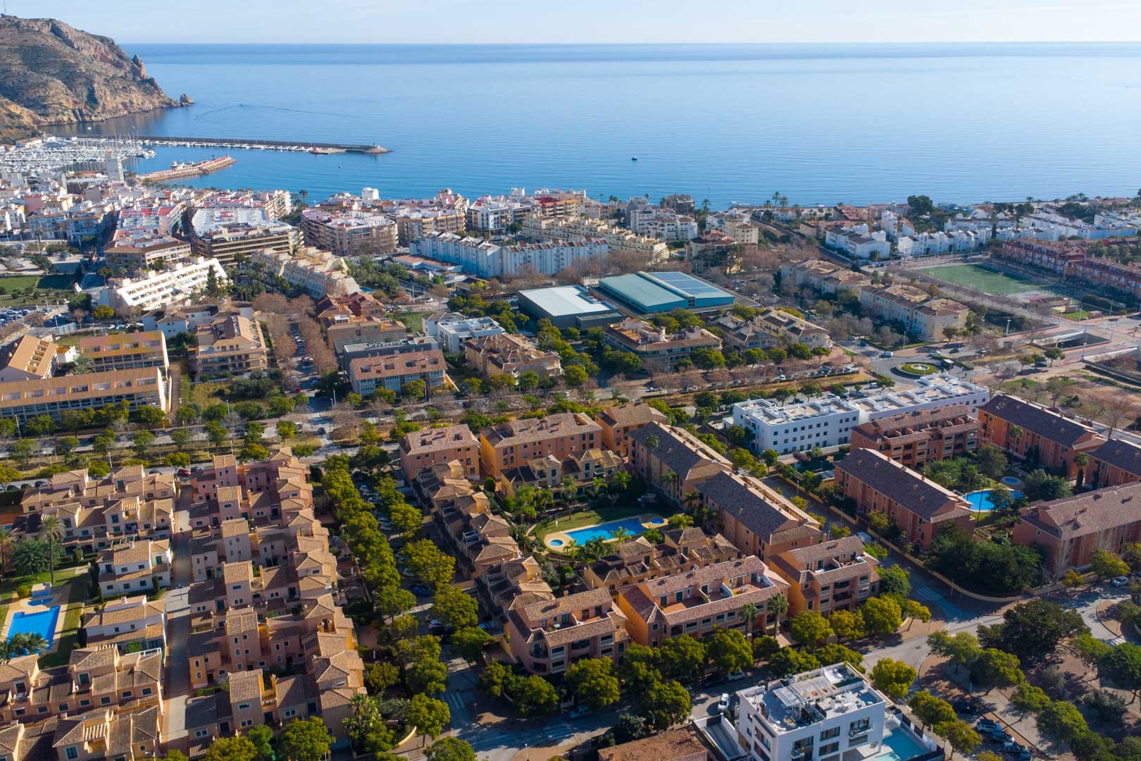 Vista aérea del complejo Floridamar en Jávea, destacando su piscina comunitaria y la cercanía estratégica al puerto y al mar Mediterráneo.