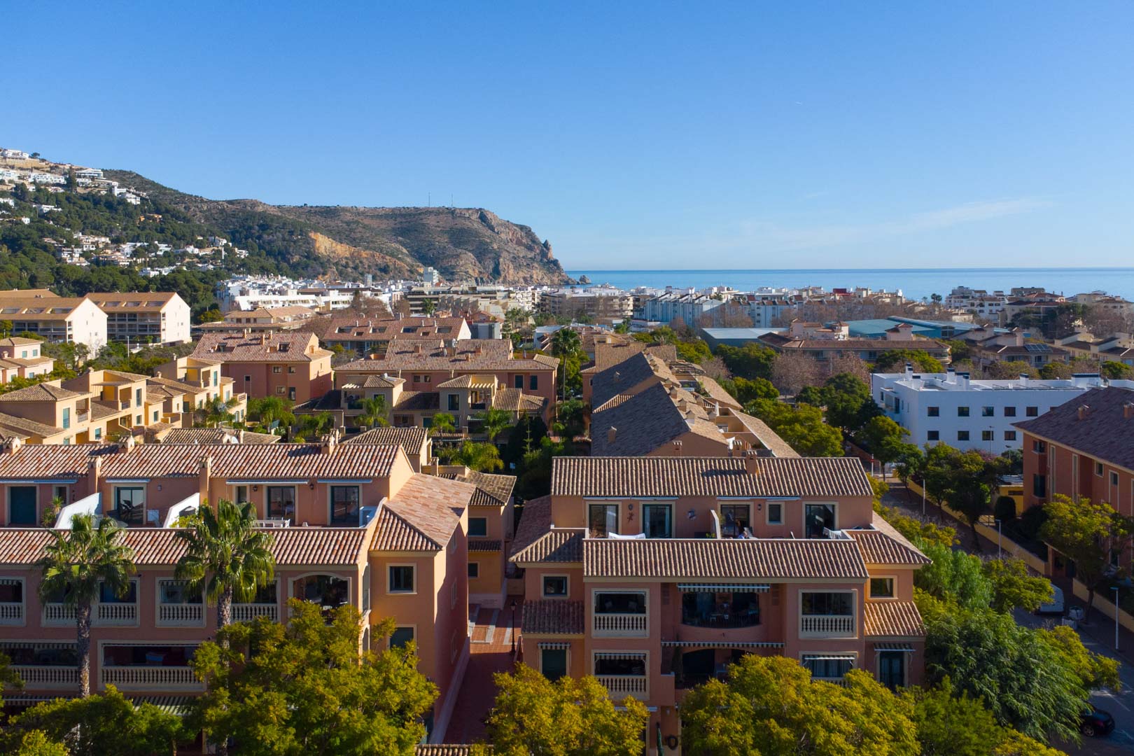 Vista aérea panorámica del complejo Floridamar con tejados de terracota, vistas al mar Mediterráneo y el emblemático Cabo de San Antonio al fondo bajo un cielo despejado.