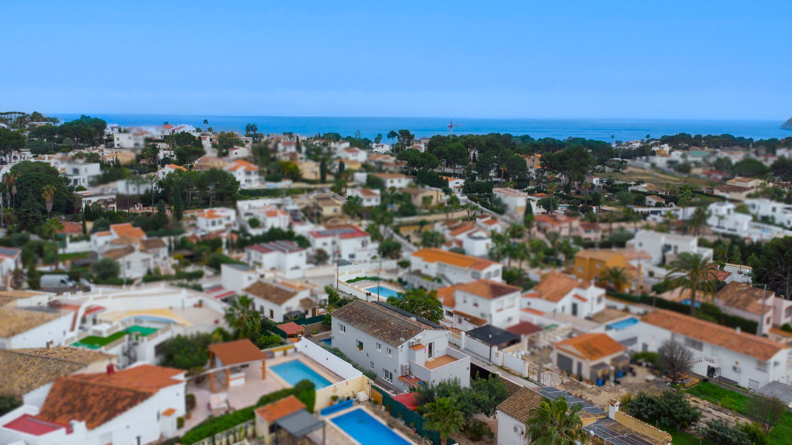 Vista aérea de la urbanización Carrio en Calpe, mostrando la cercanía al mar Mediterráneo y la disposición de las villas con piscinas privadas.