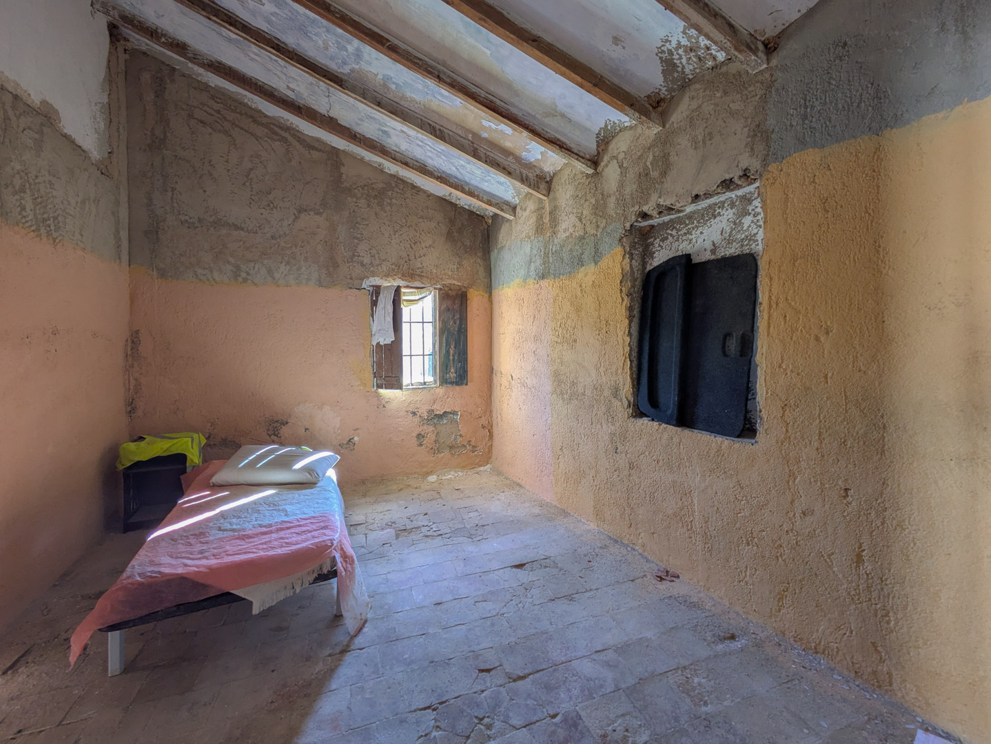 Interior rústico con vigas de madera a la vista, suelos de barro originales y paredes para reformar con entrada de luz natural.
