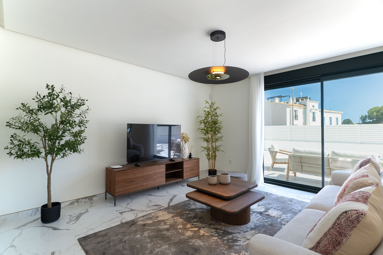 Salón contemporáneo con suelo de gres porcelánico efecto mármol, mobiliario de madera y grandes ventanales correderos que conectan con la terraza exterior.