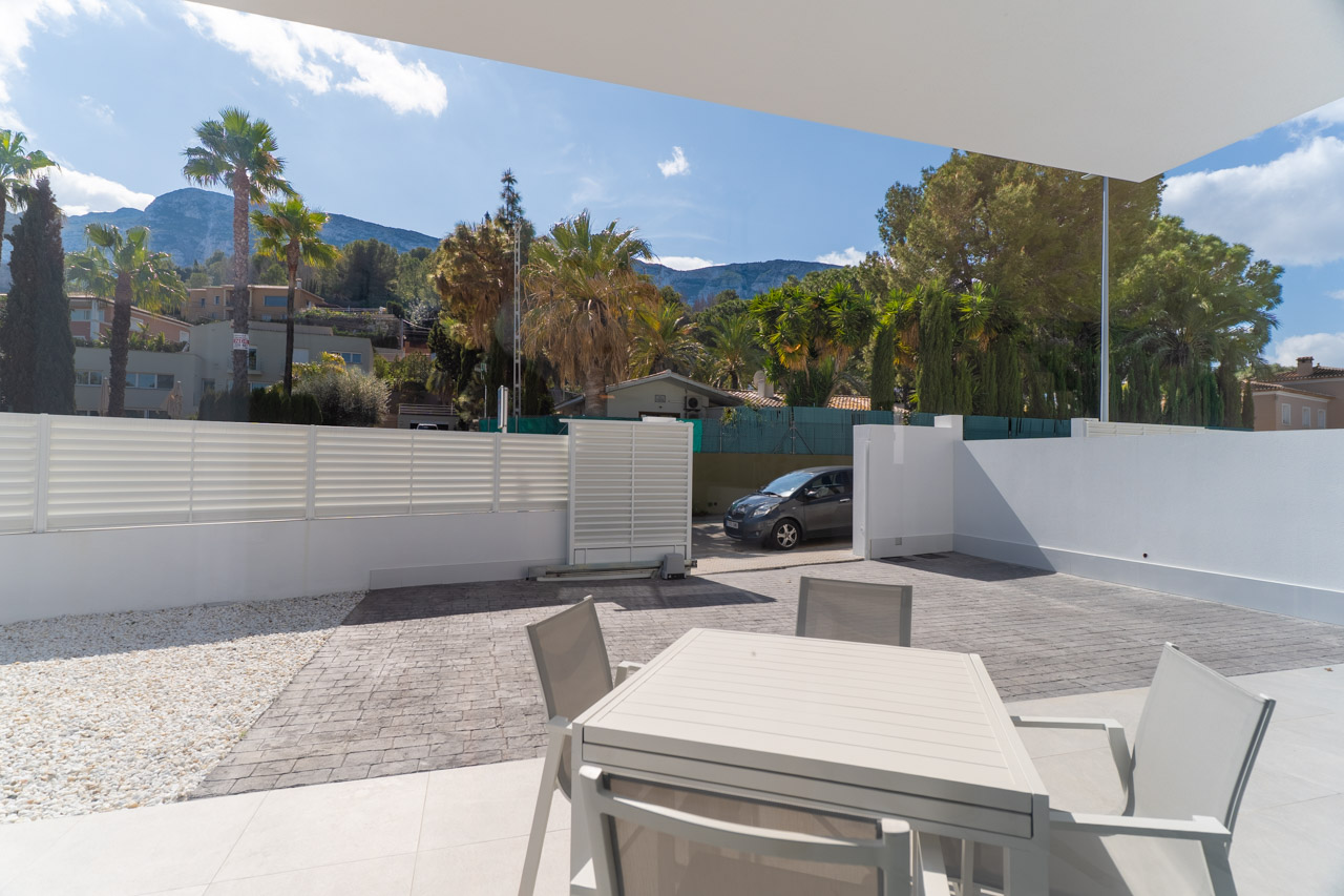 Terraza exterior con comedor de verano y zona de aparcamiento privada. Ofrece vistas despejadas al macizo del Montgó bajo un diseño arquitectónico moderno y funcional.