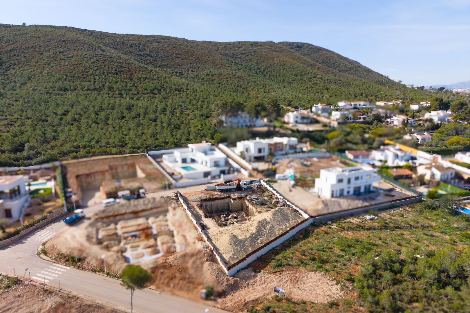 Vista aérea de la parcela en construcción en Valsol, mostrando la fase inicial de excavación y cimentación rodeada de villas modernas y colinas mediterráneas.