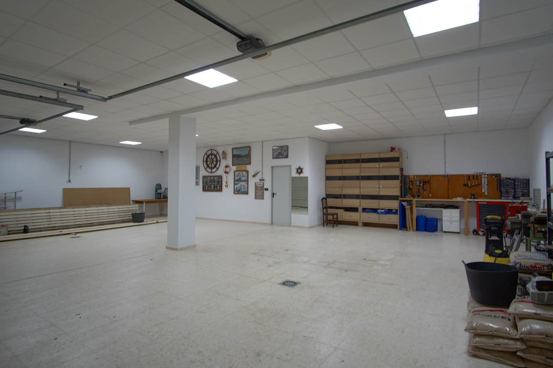 Amplio garaje con capacidad para varios vehículos, zona de taller equipada, techos técnicos con iluminación LED y suelos cerámicos de alta resistencia.
