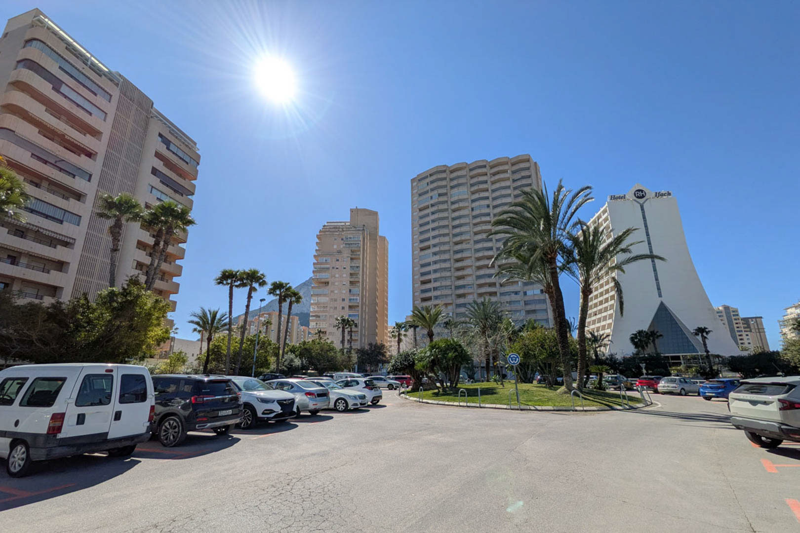 Vista exterior de una zona urbana en Calpe, destacando edificios residenciales de gran altura, el Hotel RH Ifach y amplias zonas de aparcamiento público.