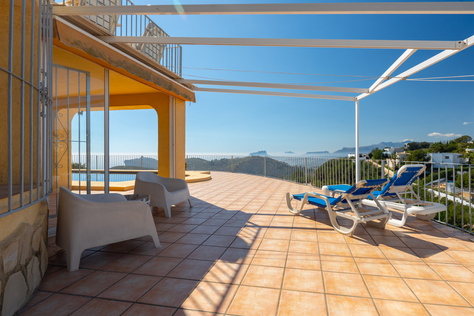 Amplia terraza solárium con baldosas de barro, pérgola metálica y vistas panorámicas al mar y las montañas de la Costa Blanca.