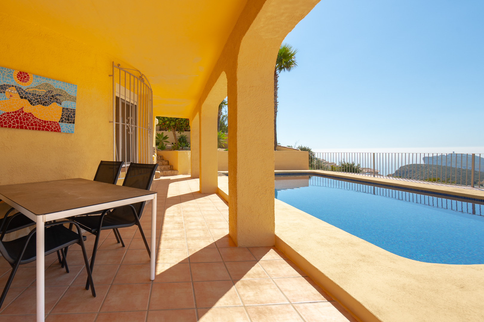 Terraza cubierta con arcos tradicionales, zona de comedor exterior y piscina privada con vistas panorámicas al mar y al Cap d'Or de Moraira.
