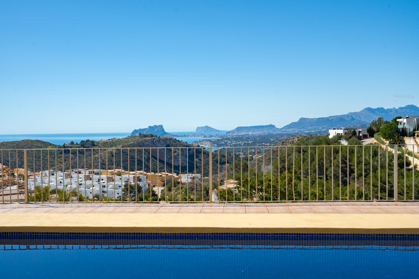 Vistas panorámicas desde la piscina hacia el Peñón de Ifach y la costa de Calpe, con la Sierra de Bernia de fondo bajo un cielo despejado.