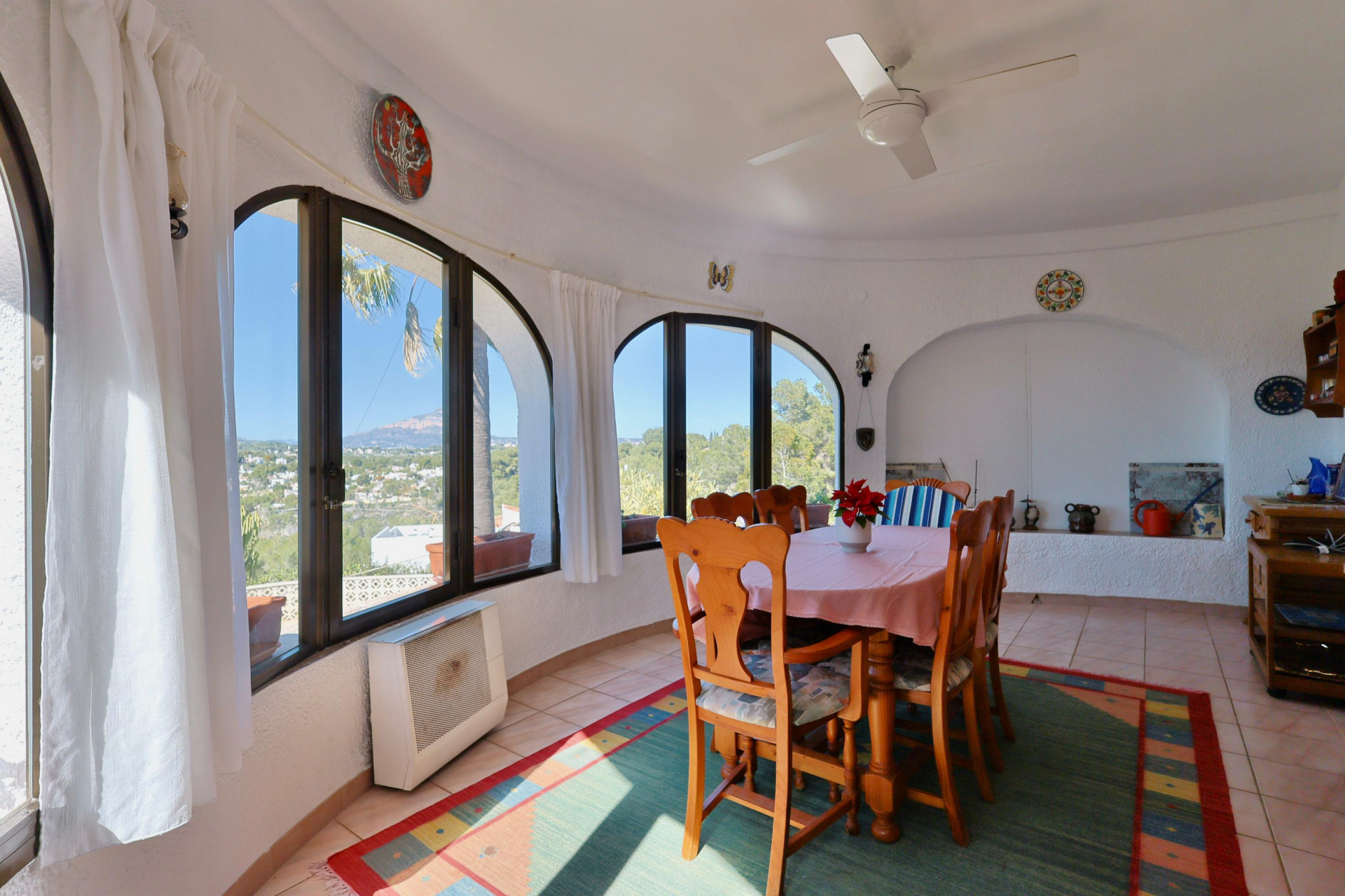 Luminoso comedor con amplios ventanales arqueados y vistas panorámicas al paisaje de Jávea.