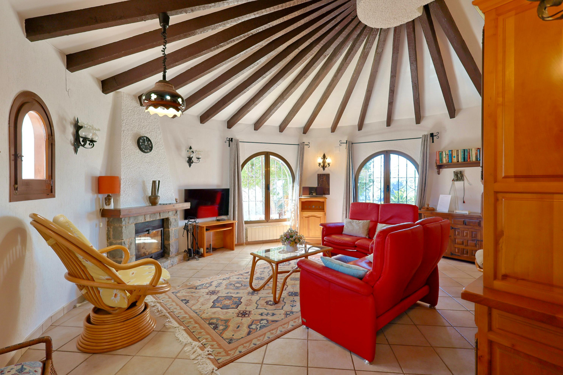 Salón circular con vigas de madera vistas y chimenea de piedra.