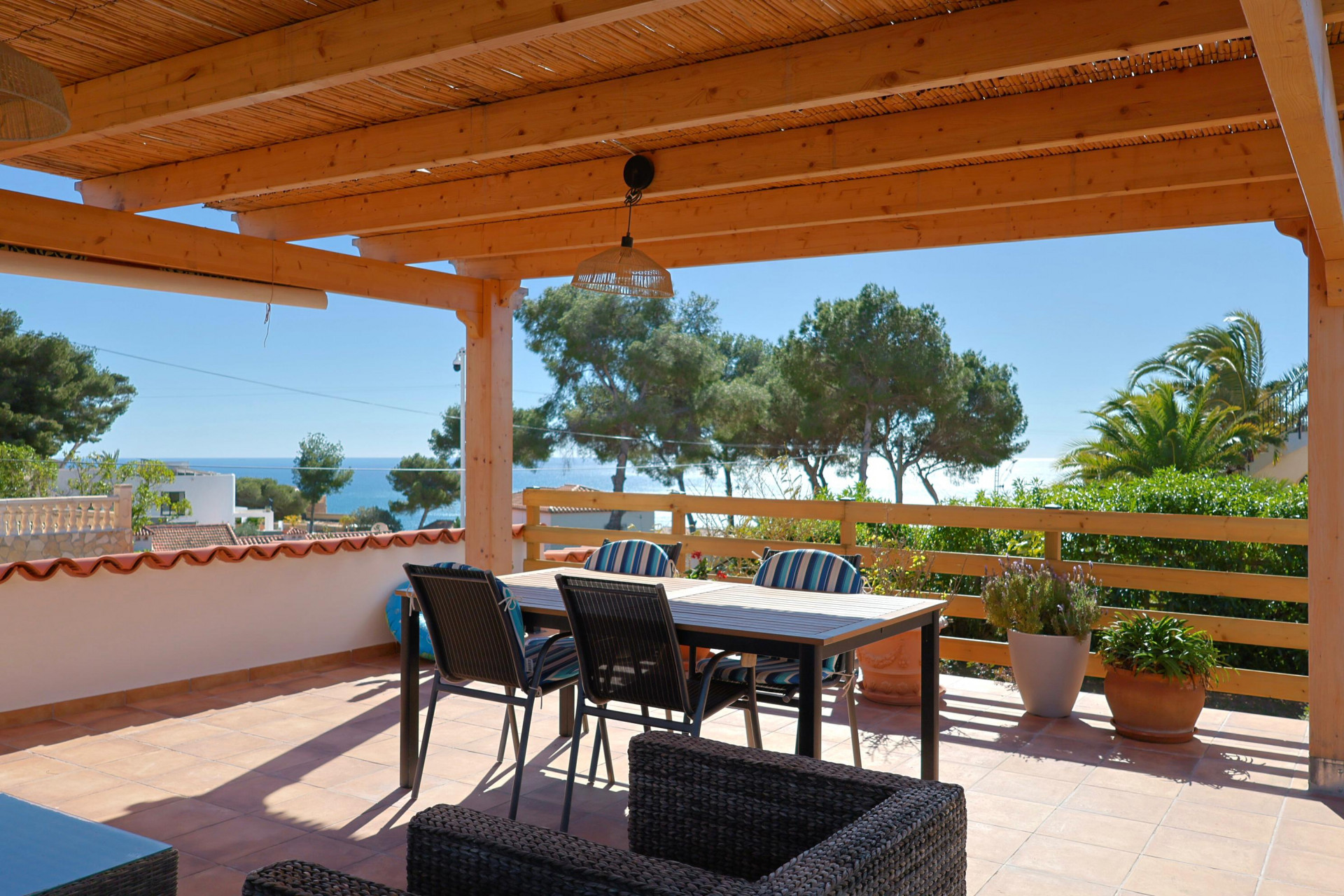 Terraza cubierta con vistas al mar y mobiliario de comedor.