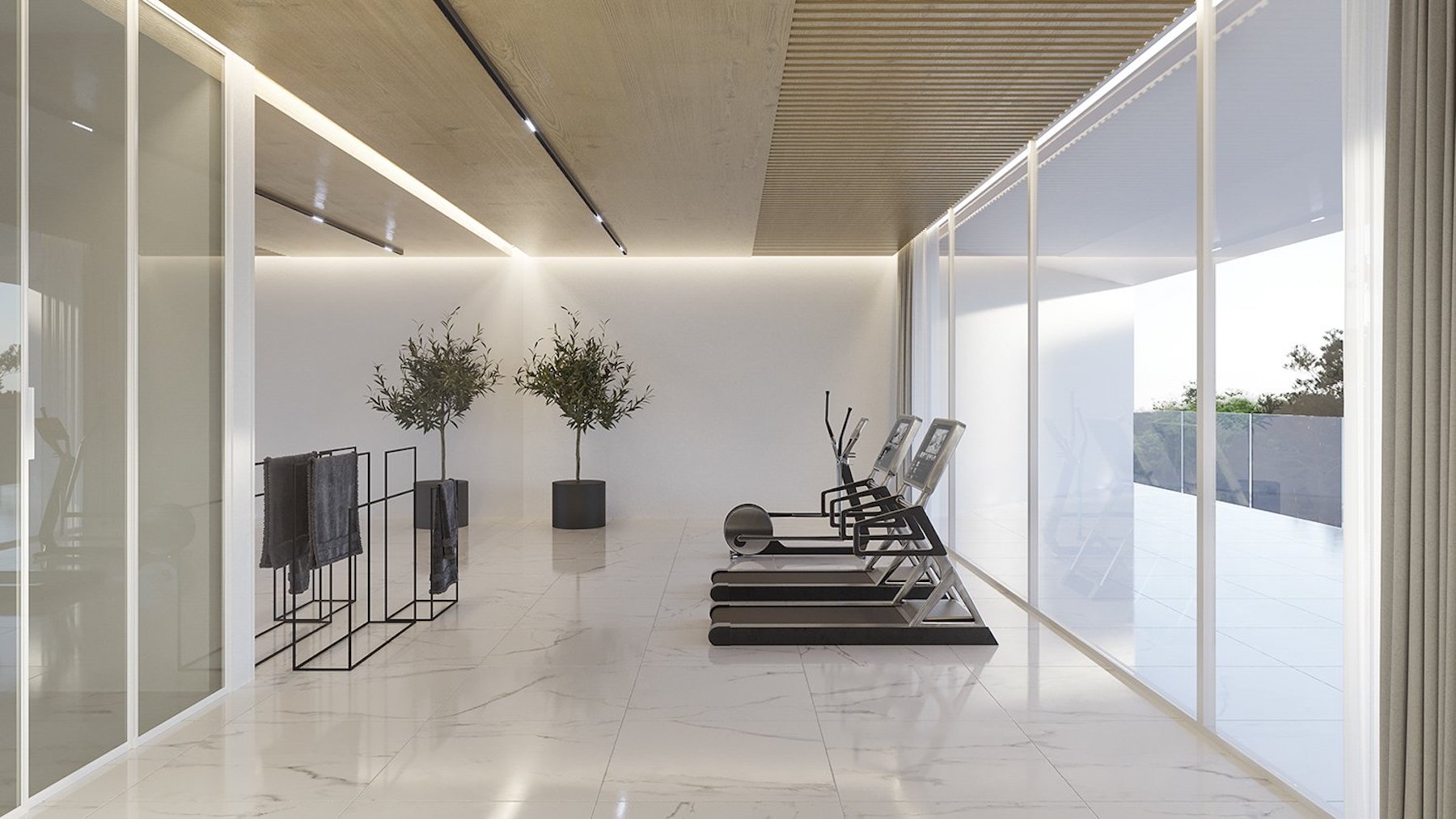 Gimnasio privado con suelos de mármol blanco, techos de madera con iluminación lineal y amplios ventanales con vistas al exterior.